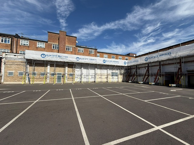 Elm Site Services branded hoarding along a scaffolded building