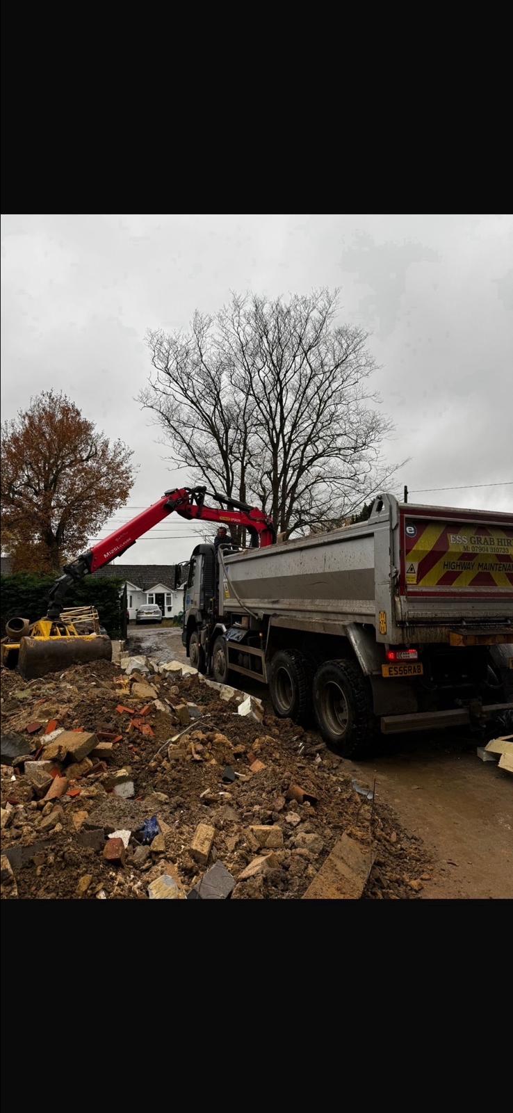 Elm Site Services grab lorry loading spoil beside a residential site