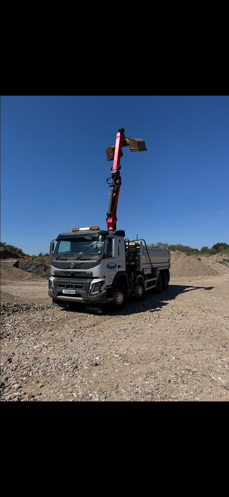Elm Site Services grab lorry with the crane raised on a material stockpile