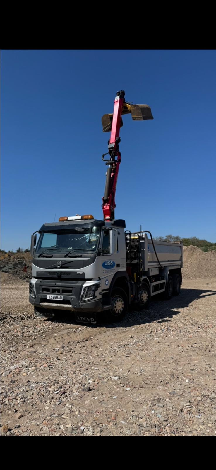 Elm Site Services grab lorry with the grab raised against a clear sky